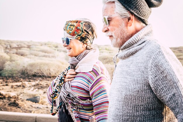 Pareja de moda feliz personas mayores en actividad de ocio al aire libre juntos en pareja - estación fría y mujer alegre con marido en relación - cielo blanco claro