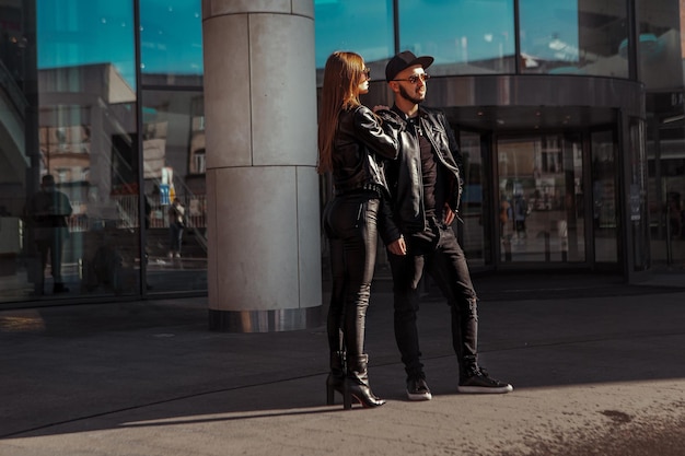 Pareja de moda posando en la ciudad en cuero y gafas de sol