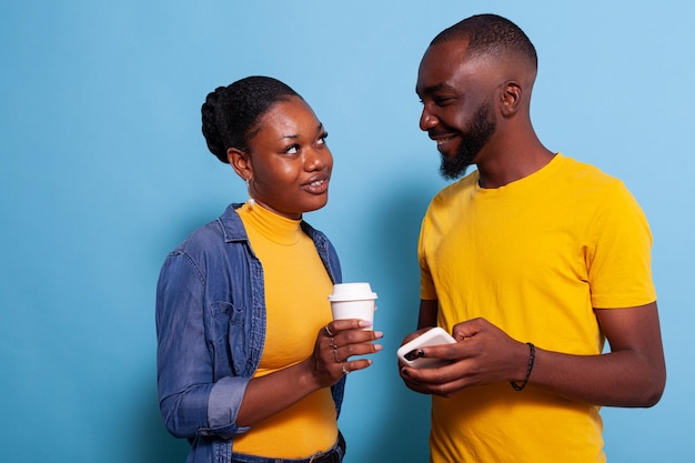 Pareja moderna con smartphone disfrutando de la risa y mirándose el uno al otro. Amantes alegres divirtiéndose con la tecnología en el teléfono móvil y navegando por Internet. Personas en relación.