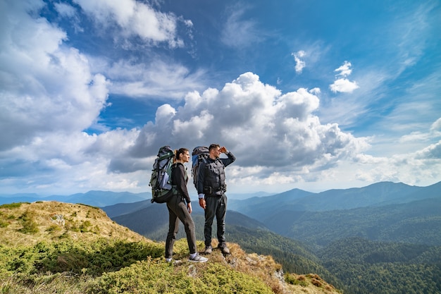 La pareja en la montaña en el pintoresco fondo de nubes