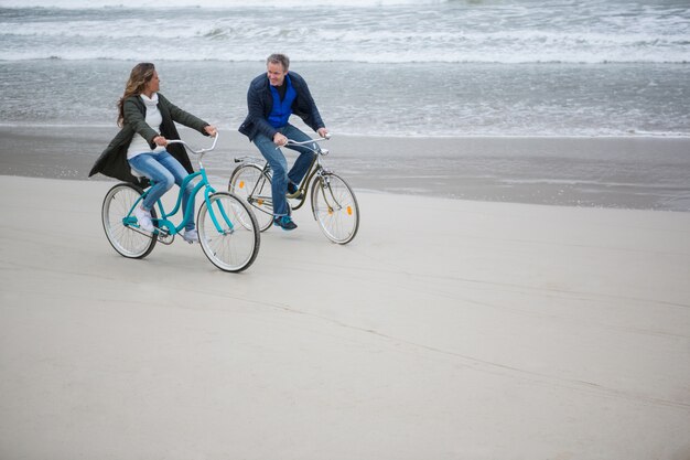 Pareja montando bicicleta en la playa