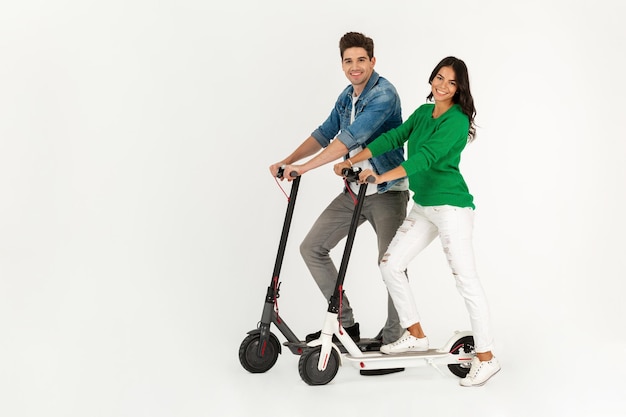 Una pareja montando en patinete eléctrico aislado sobre fondo blanco de estudio