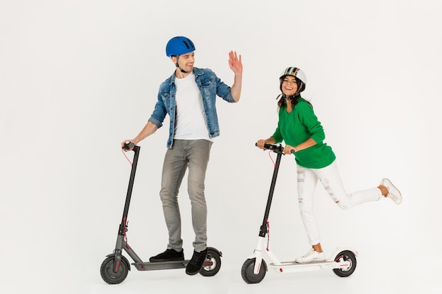 Foto una pareja montando en patinete eléctrico aislado sobre fondo blanco de estudio