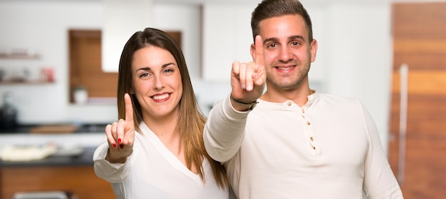 Pareja mostrando y levantando un dedo en una casa