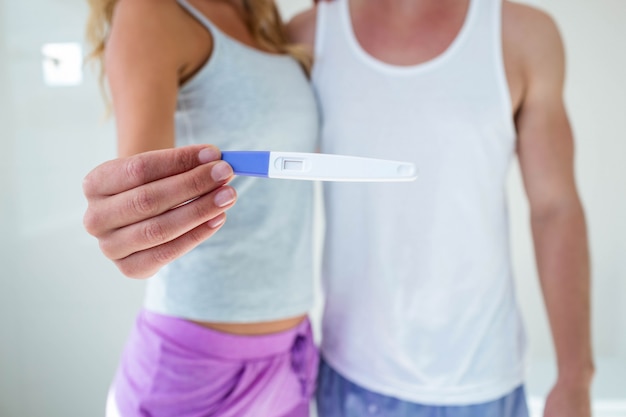 Pareja mostrando la prueba de embarazo en el baño