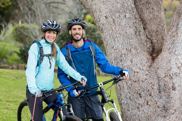 Pareja de moteros con bicicleta de montaña en campo