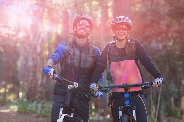 Pareja de moteros con bicicleta de montaña en campo