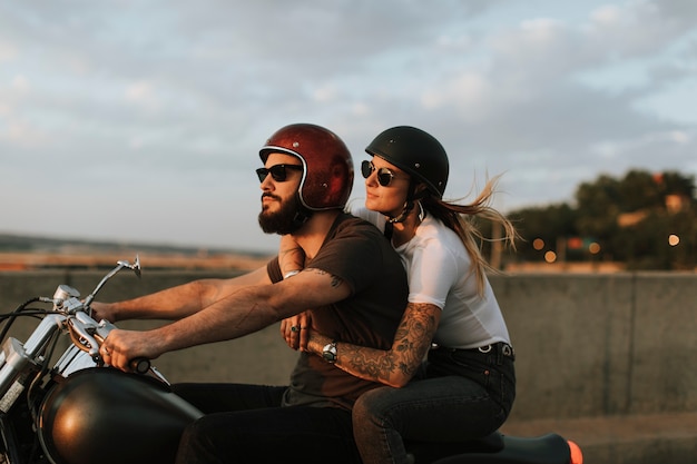 Pareja de motociclistas cabalgando por la carretera en la puesta de sol