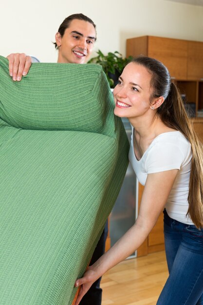 Pareja moviendo muebles en la habitación