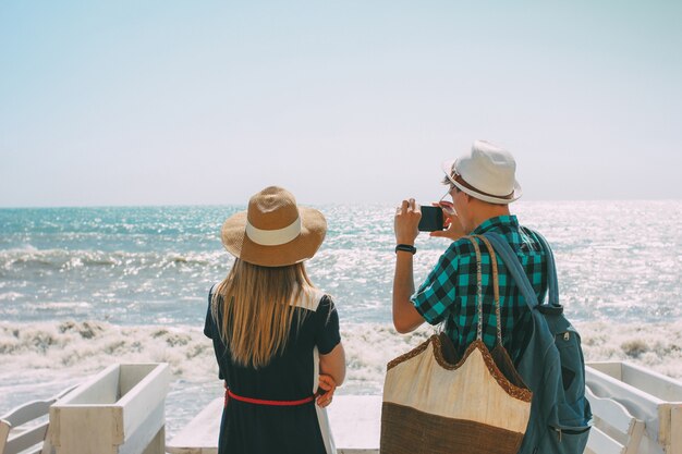 Pareja mujer y hombre mirando y haciendo fotos en el mar tempestuoso