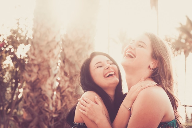 Pareja de mujeres jóvenes se divierten juntos abrazándose y riendo mucho en amistad o relación amor del mismo sexo o estilo de vida de amigos mujeres agradables disfrutan de actividades de ocio al aire libre al aire libre con sol