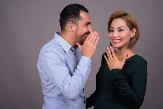 Foto pareja multiétnica en el amor contra la pared gris