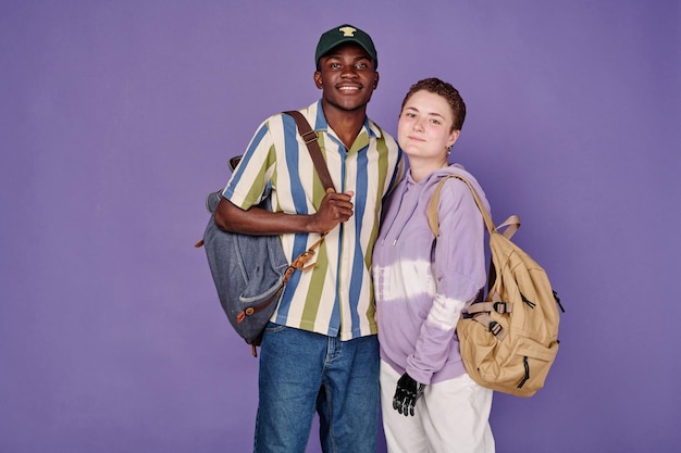 Pareja multiétnica de estudiantes con mochilas.