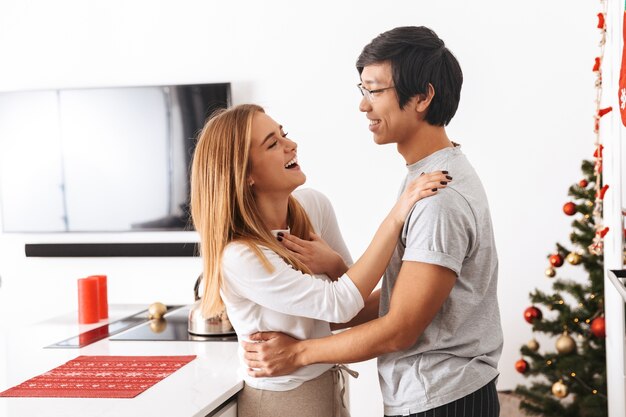 pareja multiétnica, hombre y mujer, de pie, en, brillante, cocina, y, abrazar, juntos