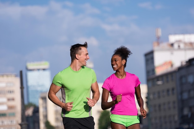 Una pareja multiétnica joven y saludable trotando en la ciudad en un día soleado de verano
