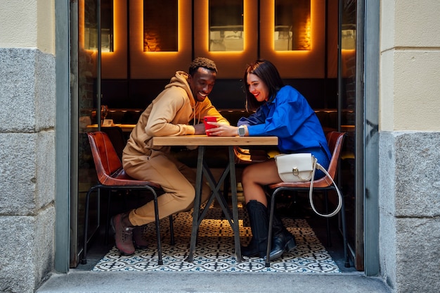 Foto pareja multiétnica mirando smartphone en un restaurante