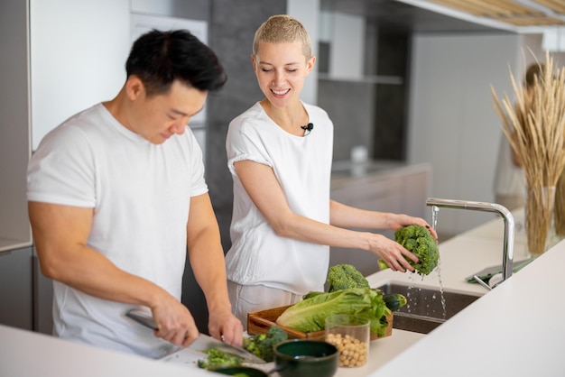 Pareja multirracial cocinar ensalada juntos en la cocina