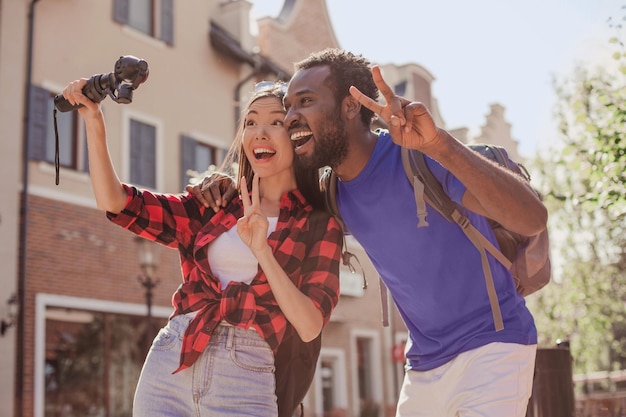 Pareja multirracial haciendo video con cámara en la calle durante el día