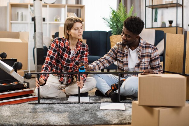 Foto pareja multirracial montando muebles en casa