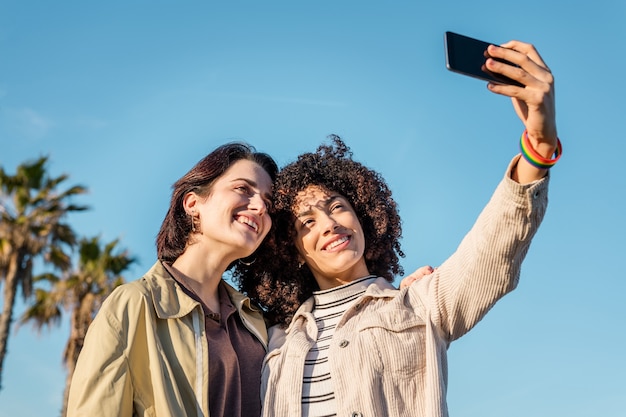 Pareja multirracial de mujeres homosexuales tomando una foto