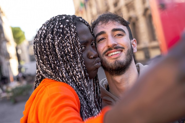 Pareja multirracial tomando selfie en la calle