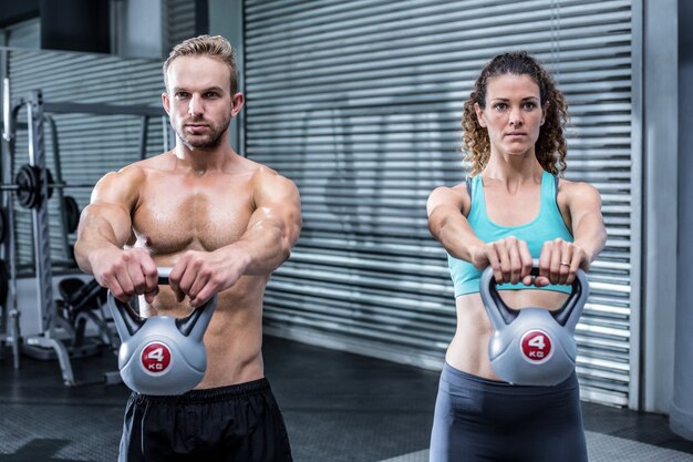 Una pareja muscular levantando kettlebells