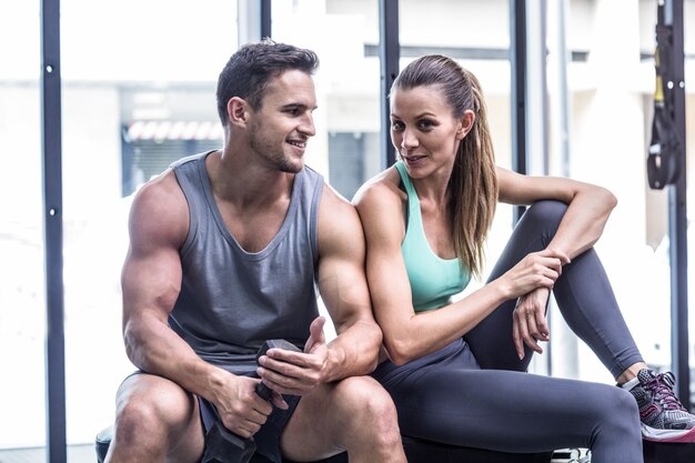 Foto pareja muscular sentado en el banquillo