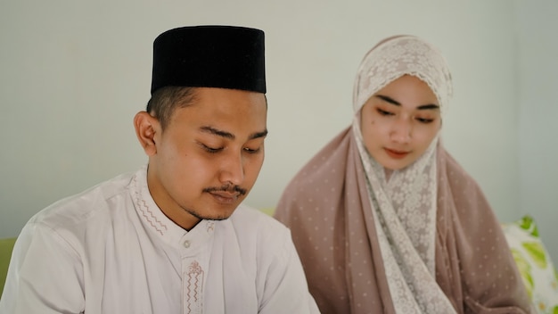 Pareja musulmana asiática rezando juntos en casa