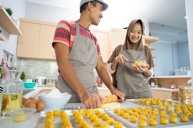 Pareja musulmana haciendo bocadillos nastar juntos en la cocina durante el ramadán