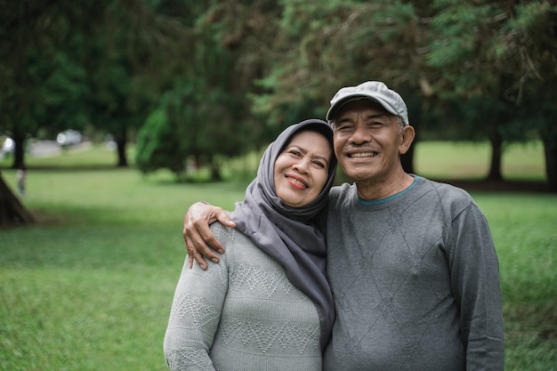 Pareja musulmana en el parque sonriendo y mirando a cámara