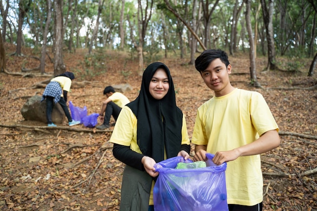 Pareja musulmana sonriente voluntario con bolsa de basura