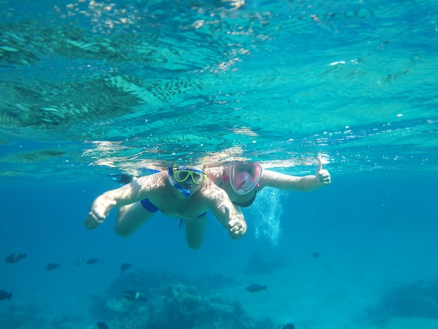 Pareja nadar bajo el agua en máscaras en el mar