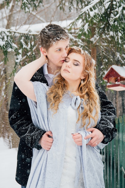 Pareja en la naturaleza en invierno durante una nevada