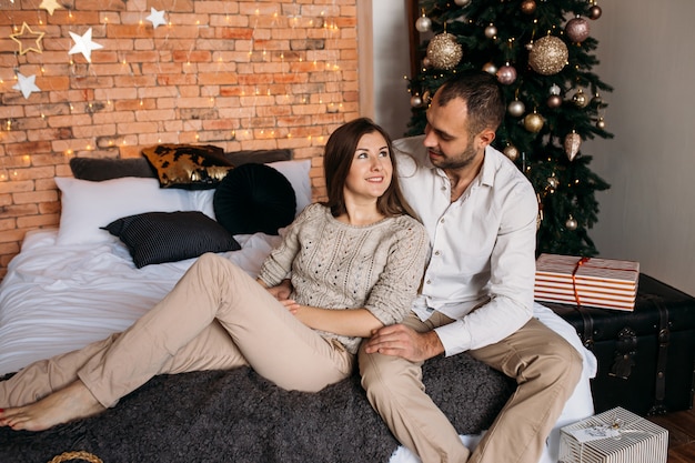 Pareja en Navidad en casa en la cama cerca