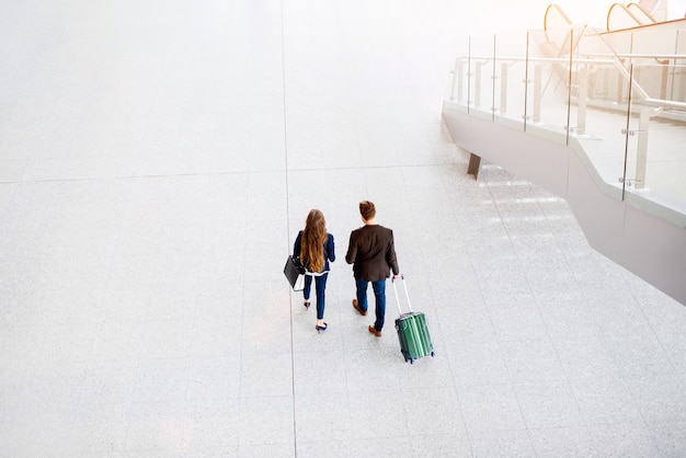 Pareja de negocios caminando con equipaje en el aeropuerto. Vista superior de gran angular con espacio de copia