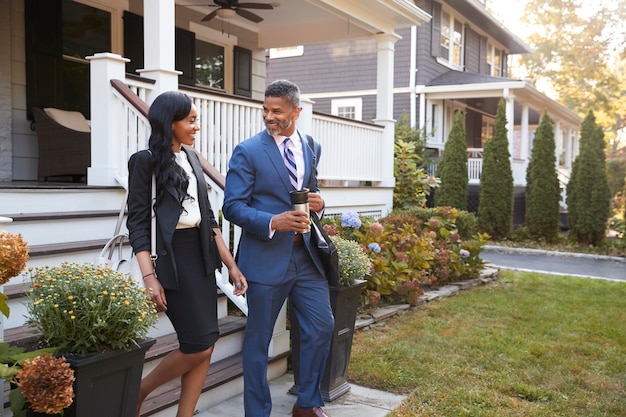 Pareja de negocios dejando casa suburbana para ir al trabajo