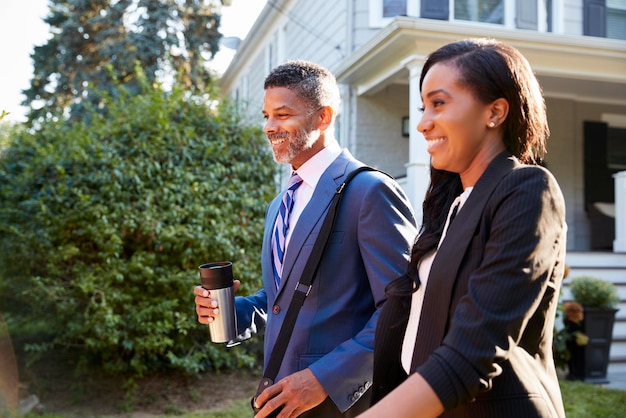 Pareja de negocios dejando casa suburbana para ir al trabajo