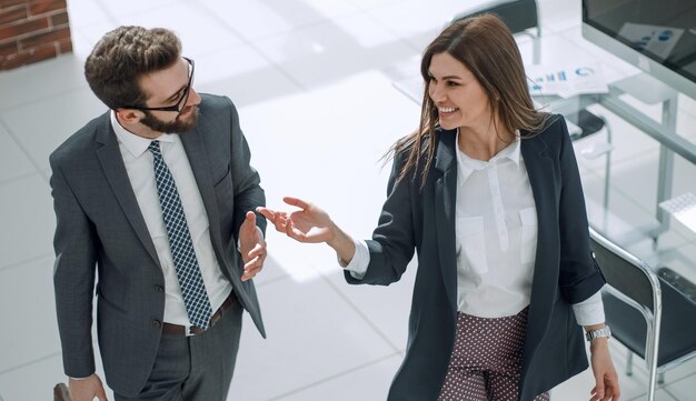 Foto pareja de negocios discutiendo asuntos de negocios mientras camina por la oficina