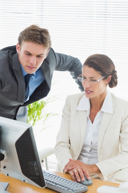 Foto pareja de negocios elegantemente vestida usando la computadora en una oficina brillante