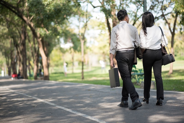 Pareja de negocios hablando al aire libre y caminando en un parque