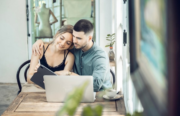 Pareja de negocios Mujer alegre que usa la computadora portátil en la cafetería Joven empresario y novia feliz sonriendo mientras trabajan juntos Dos jóvenes empresarios se sientan juntos en la mesa