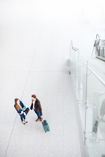 Pareja de negocios de pie junto con el equipaje en el aeropuerto. Vista superior de gran angular con espacio de copia