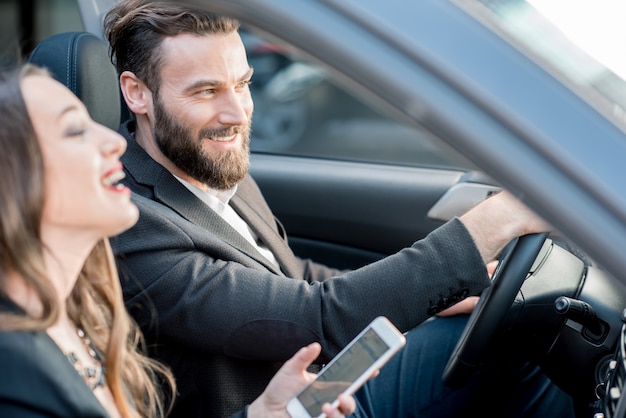 Pareja de negocios que tiene una conversación divertida mientras conduce un automóvil en la ciudad