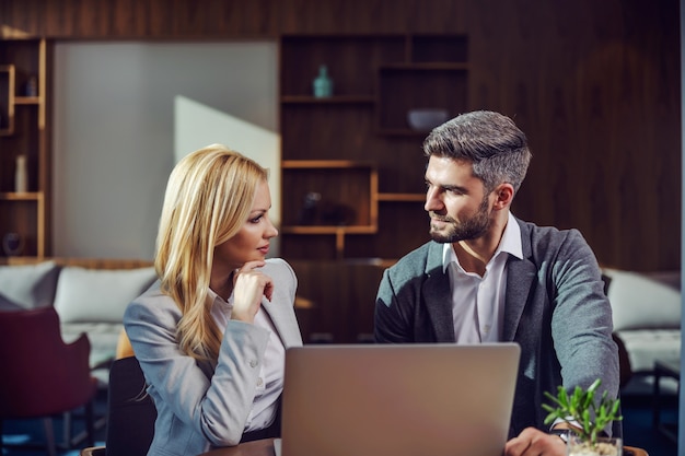 Pareja de negocios sentado en un café y tener una charla de negocios. Hay una computadora portátil sobre una mesa. Reunión de negocios, tecnología, cooperación.