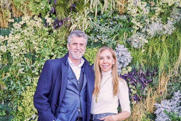 pareja de negocios en traje formal mirando a la cámara con un jardín vertical en el fondo