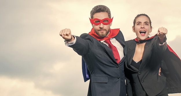 Pareja de negocios en traje de superhéroe en el espacio de copia de fondo del cielo