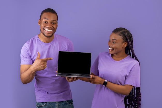 Una pareja negra emocionada que muestra la pantalla de un portátil en blanco negro