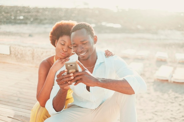 Una pareja negra, un hombre y una mujer, disfrutan juntos de la tecnología de conexión usando el teléfono móvil y la aplicación Gente moderna feliz escribiendo en un teléfono inteligente en una actividad de ocio al aire libre juntos sonriendo y divirtiéndose