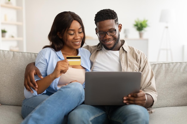 Pareja negra usando pc y tarjeta de crédito de débito en casa