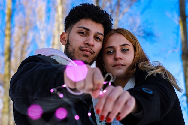 Pareja en la nieve en un día soleado en un bosque con árboles y cielo azul